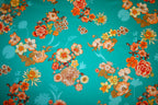 Satinvævet bomuldsstof fra Italien med turkis bund og blomsterprint i orange, creme og gyldne nuancer