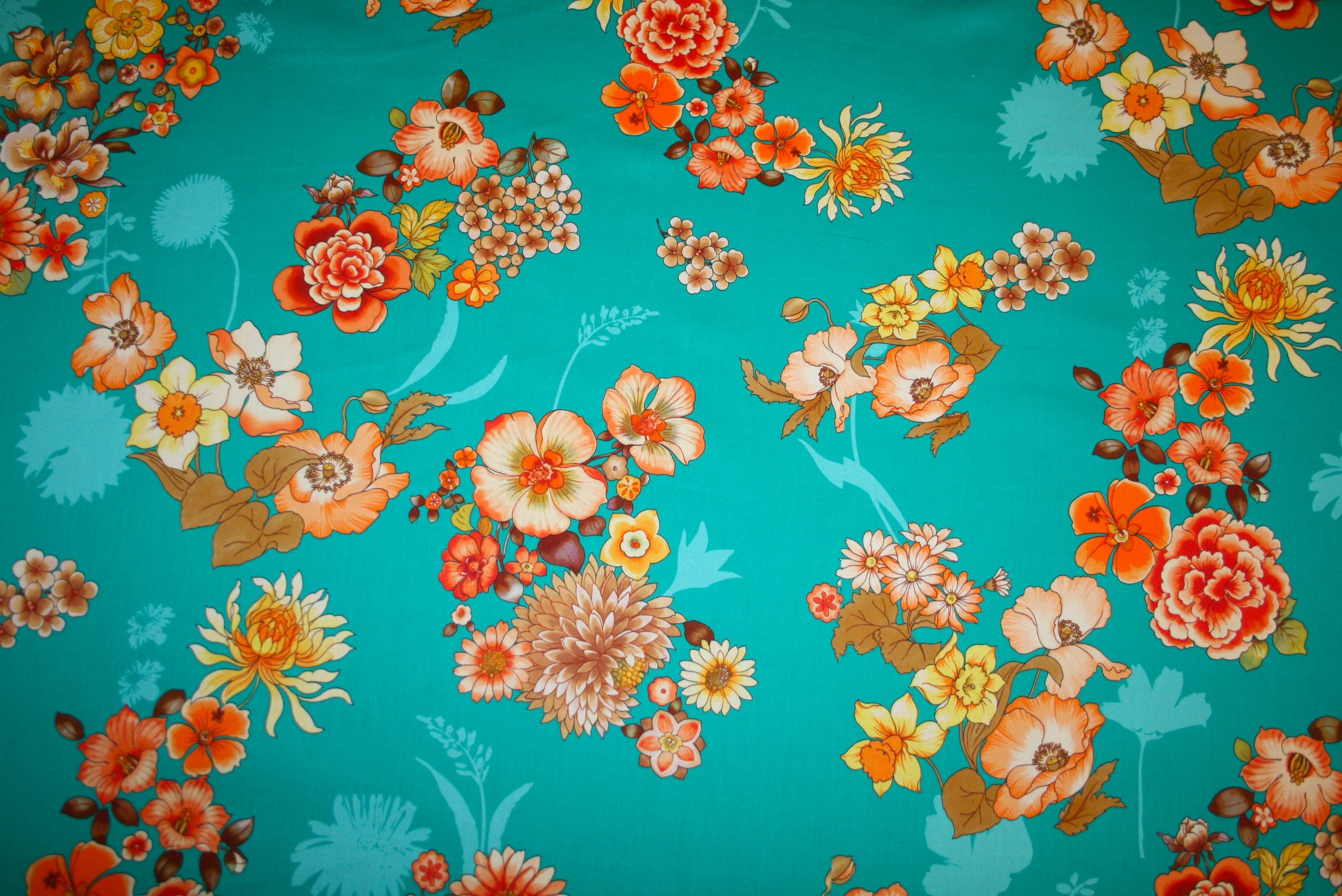 Satinvævet bomuldsstof fra Italien med turkis bund og blomsterprint i orange, creme og gyldne nuancer