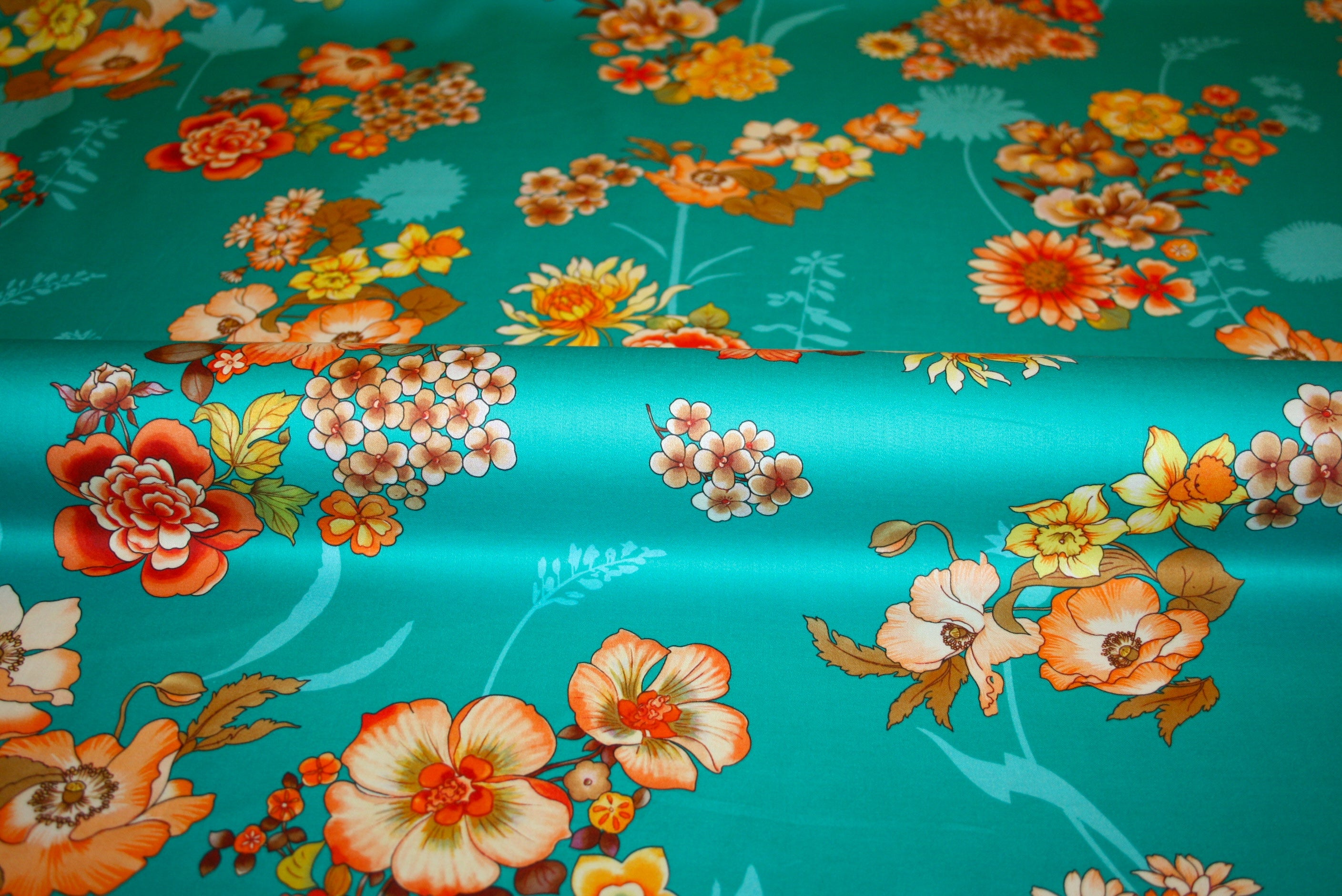 Blomstret italiensk bomuldsstof med let glans og vintageinspireret print i orange og koral