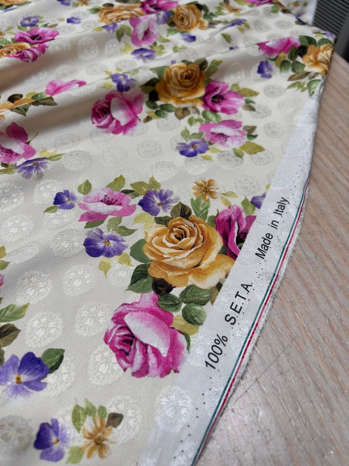 Nærbillede af jacquardvævet silke med blomsterprint og elegant tone-i-tone vævning på lys bund